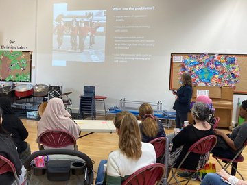 A group of parents are watching a presentation in a school hall.