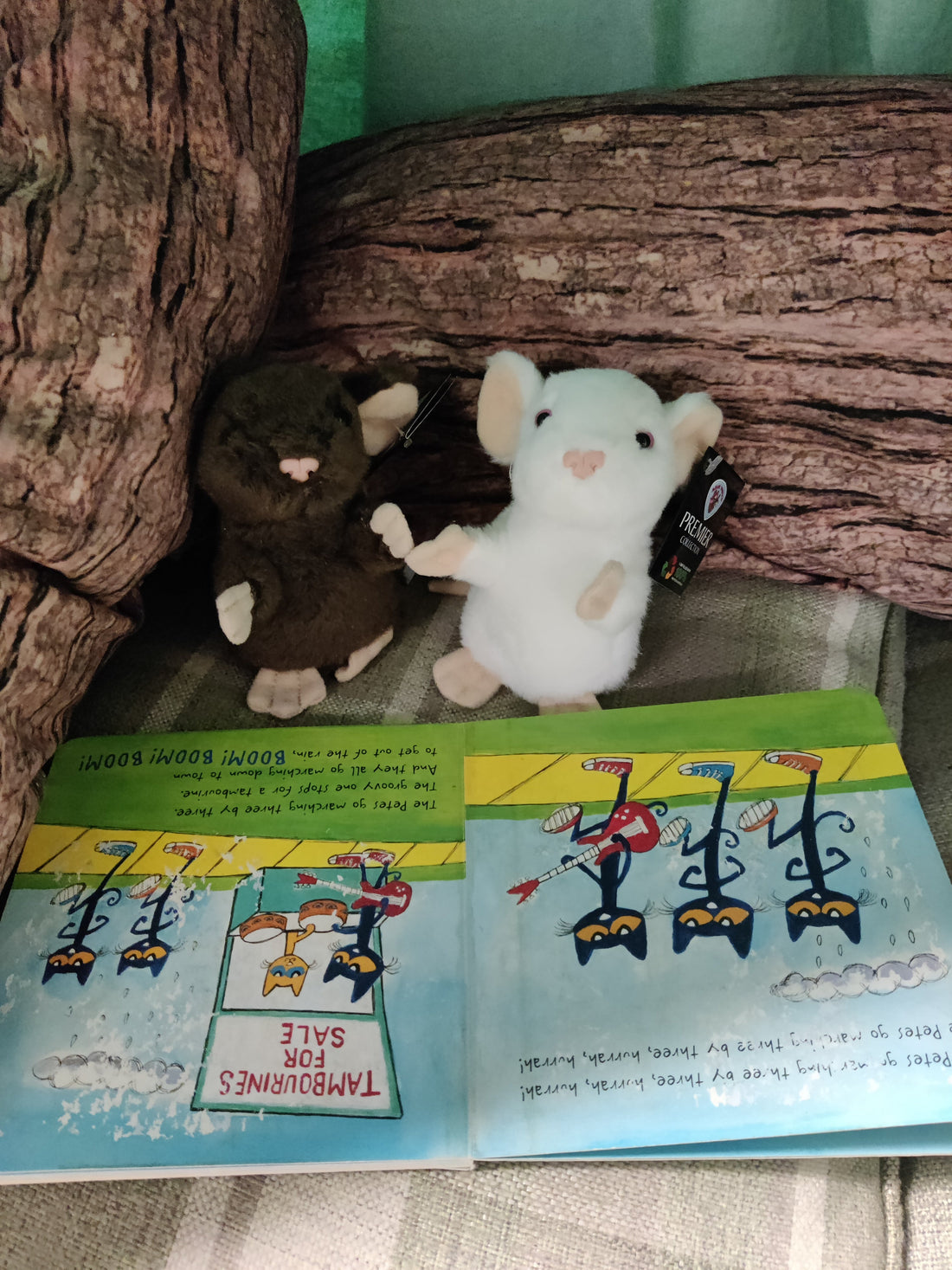 two plush mice are sitting in a den 'reading' a book about cats.