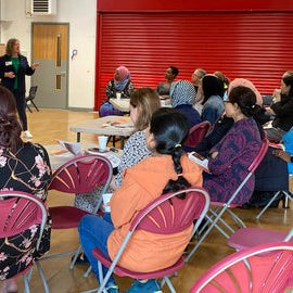 A group of parents sitting in chairs in a school hall