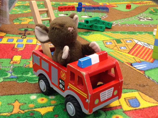 A toy mouse sits in a wooden fire engine toy